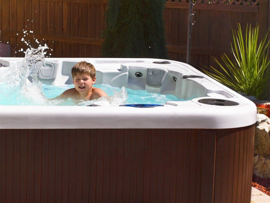 boy playing with bubbles in hot tub on the back yard