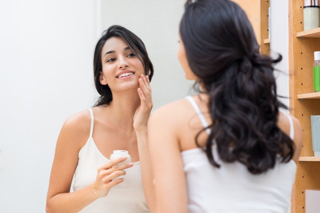 woman applying moisturizer on her face