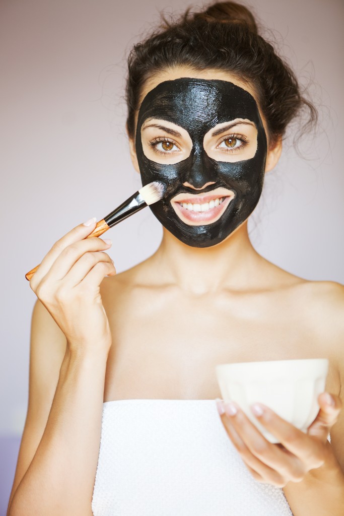 woman in towel putting a mud mask with a brush