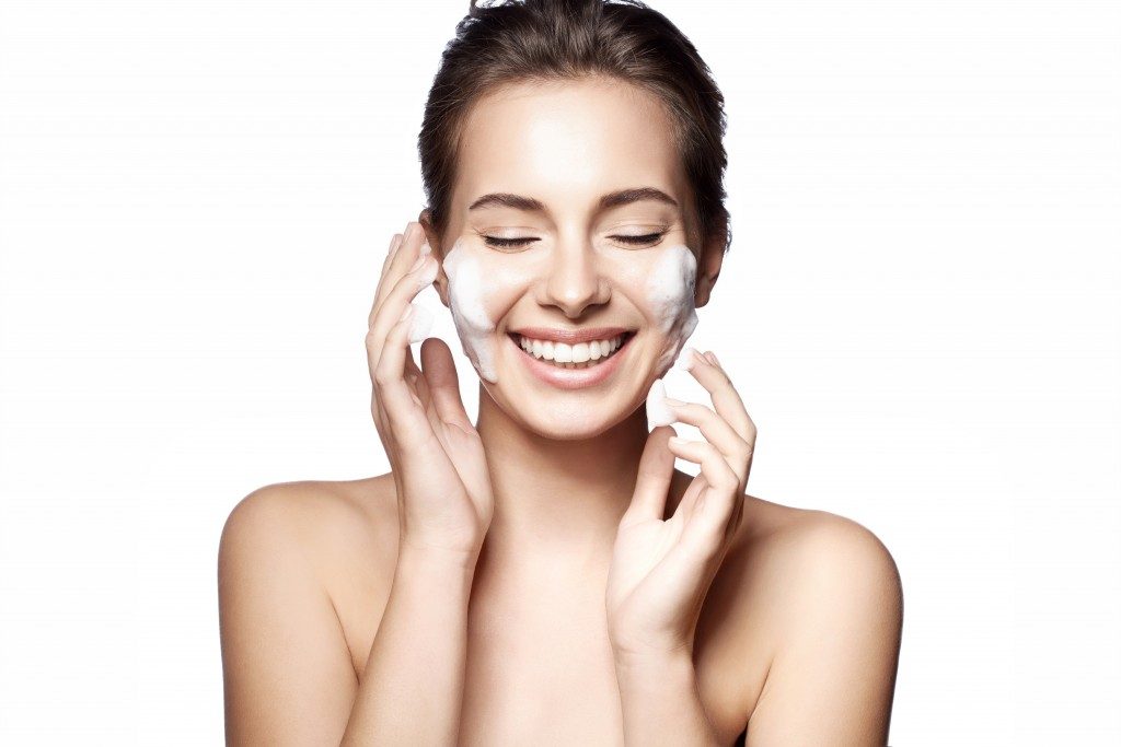 Woman happily cleanses the skin on a white background