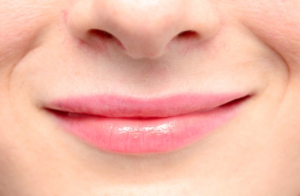 close up shot of woman's lips in pink smiling