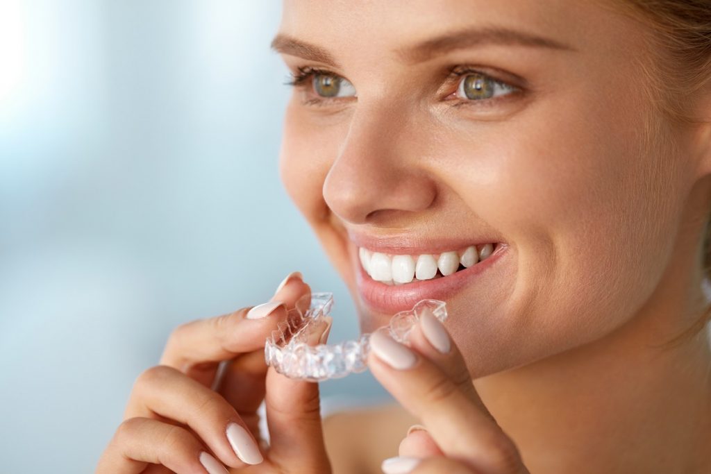 Woman smilling putting on an invisalign