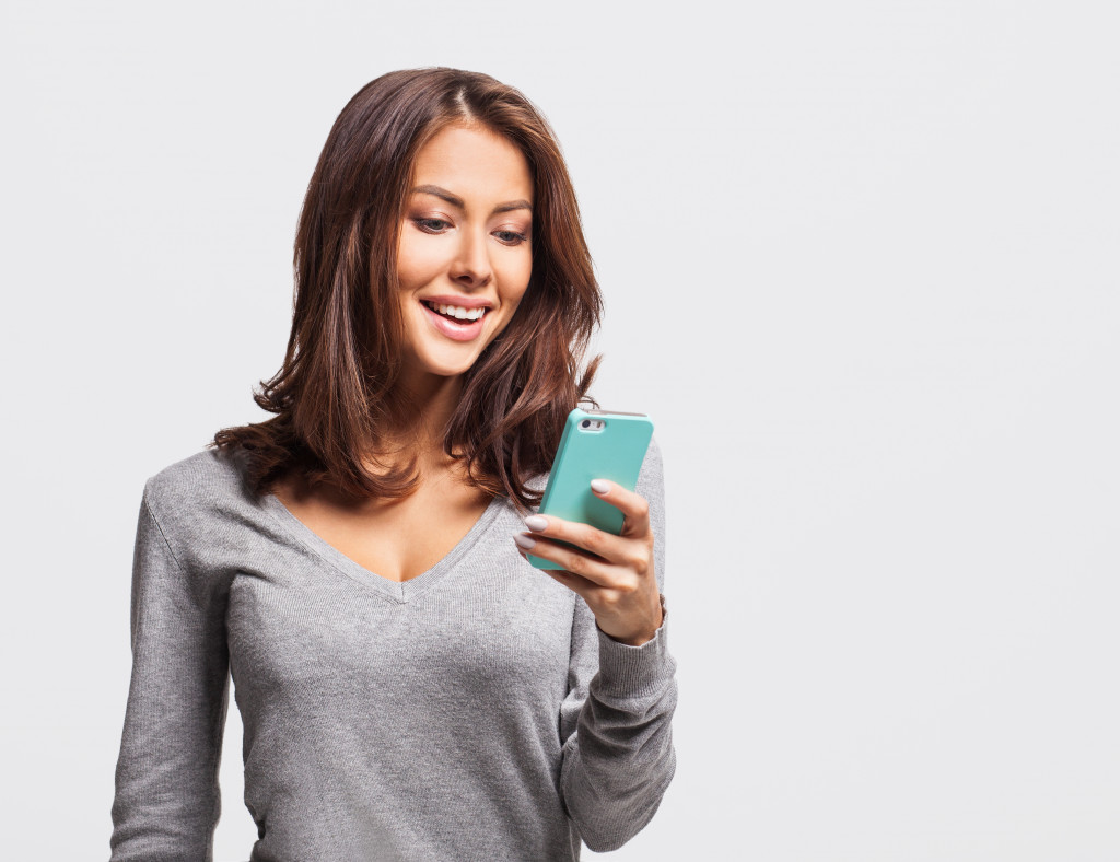 Smiling woman using her smartphone while standing.